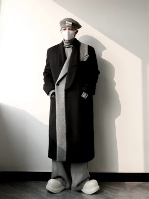 Front full-body view of a black and grey asymmetric wool blend overcoat styled with a grey turtleneck, wide-leg trousers, beret, face mask, and chunky platform sneakers