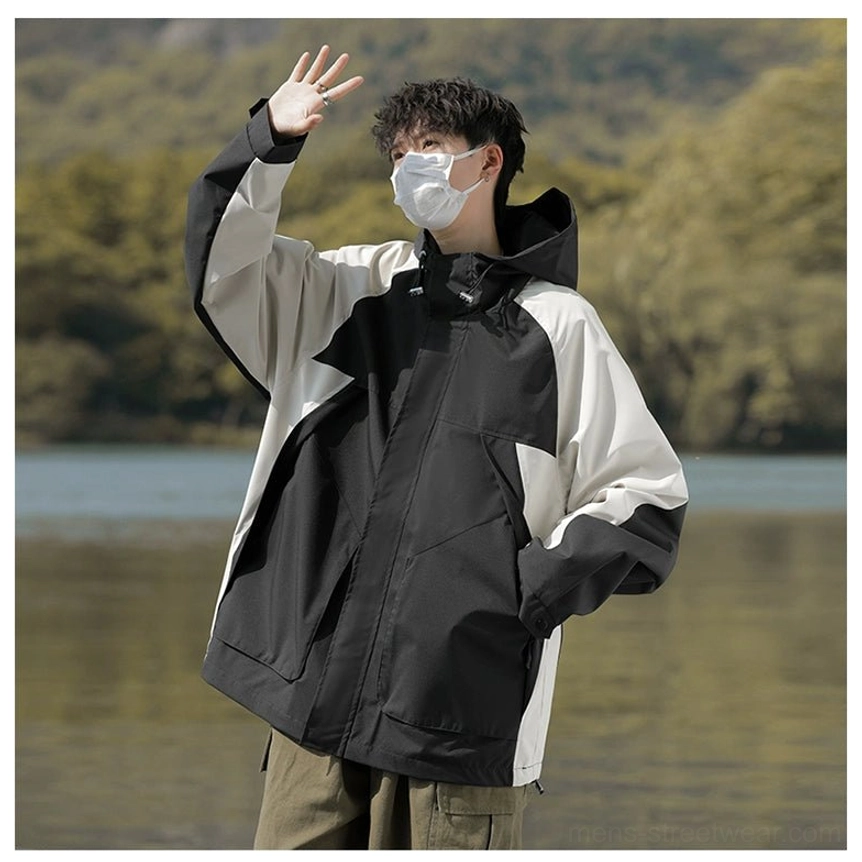 Side front view of an asymmetric black and off-white colorblock techwear jacket with hood and utility pockets
