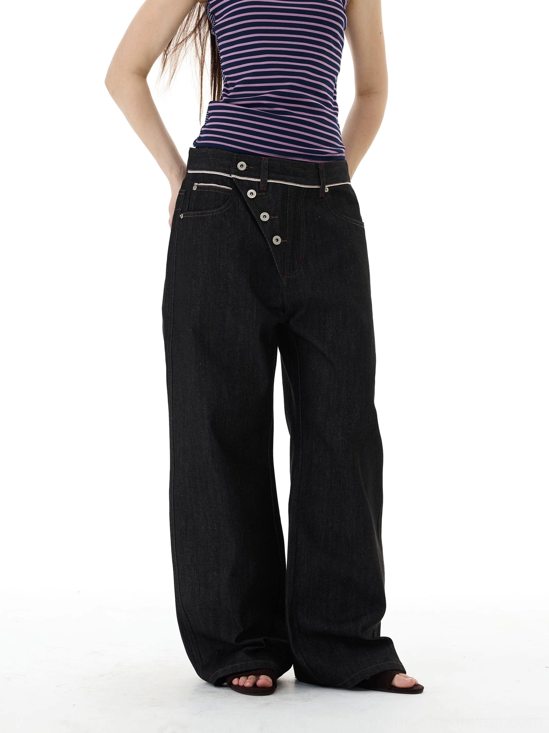 Front full-body view of oversized asymmetric button wide-leg black jeans with contrast stitching and dark denim streetwear styling