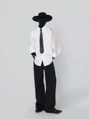 Front view of asymmetric mesh sleeve white shirt with black tie styled with black wide-leg trousers and streetwear accessories