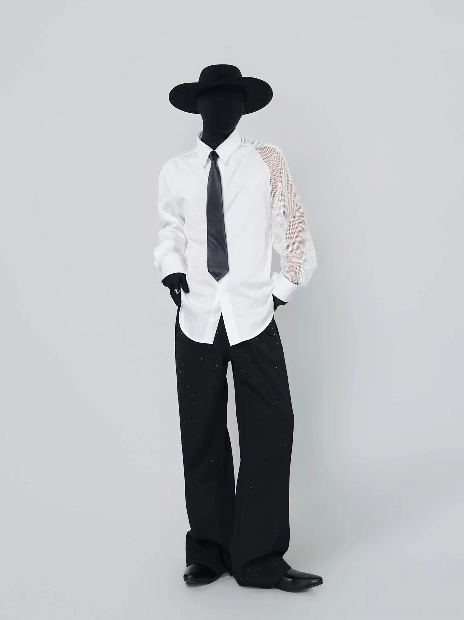 Front view of asymmetric mesh sleeve white shirt with black tie styled with black wide-leg trousers and streetwear accessories