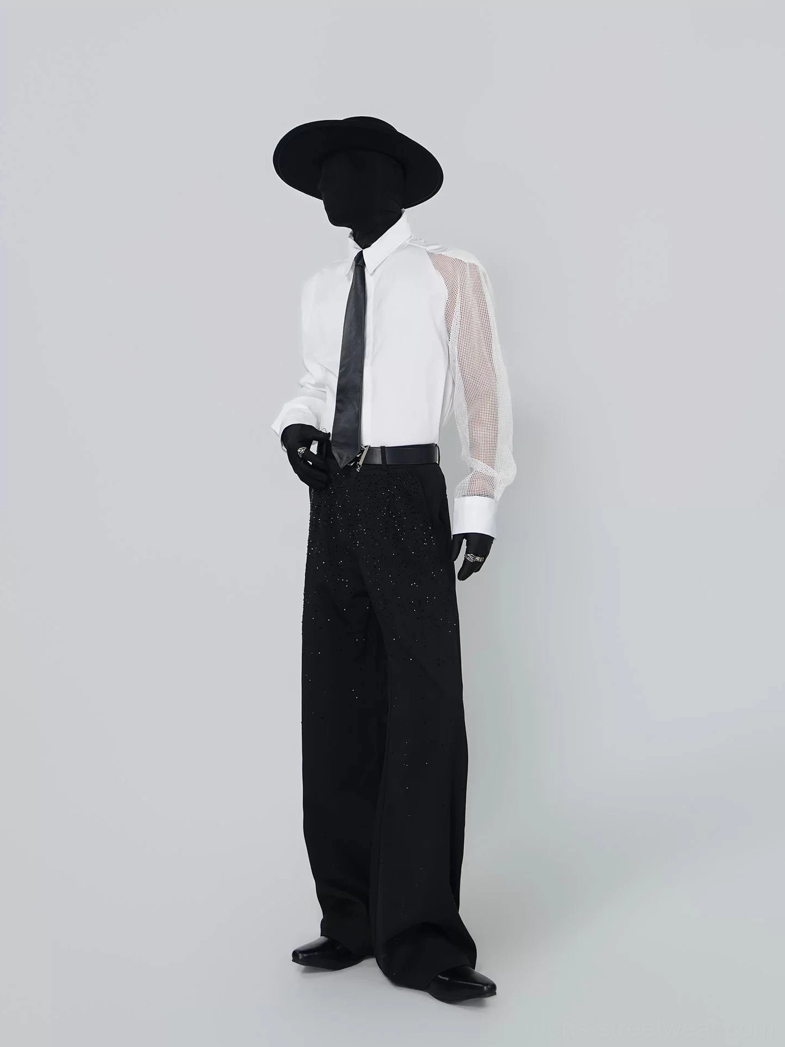 Three-quarter front view highlighting the sheer mesh sleeve on the asymmetric white shirt with black tie and leather belt