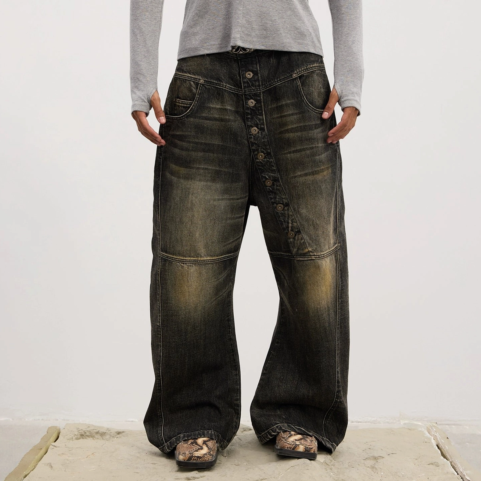 Detailed product view of asymmetric wide-leg denim jeans with diagonal button placket and oversized streetwear fit