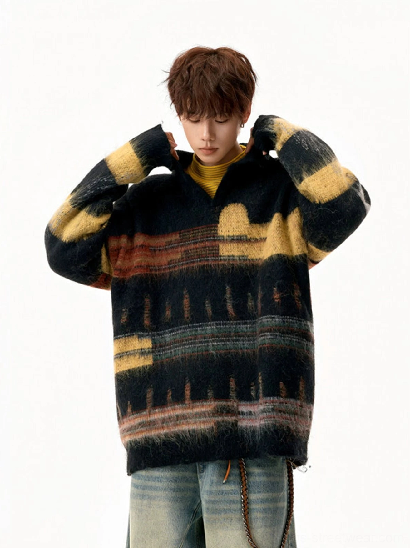 Front three-quarter view of an oversized black fuzzy knit polo sweater with retro geometric stripes, worn with a yellow inner layer and baggy jeans