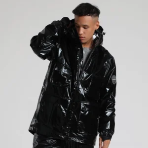 Black glossy storm shell ski jacket shown from a side three-quarter angle with cargo pockets, attached hood, embossed sleeve patch, and windproof ribbed cuffs