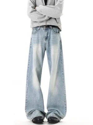 Front view of washed blue relaxed wide-leg jeans with a long stacked hem styled with a gray zip hoodie and black leather shoes