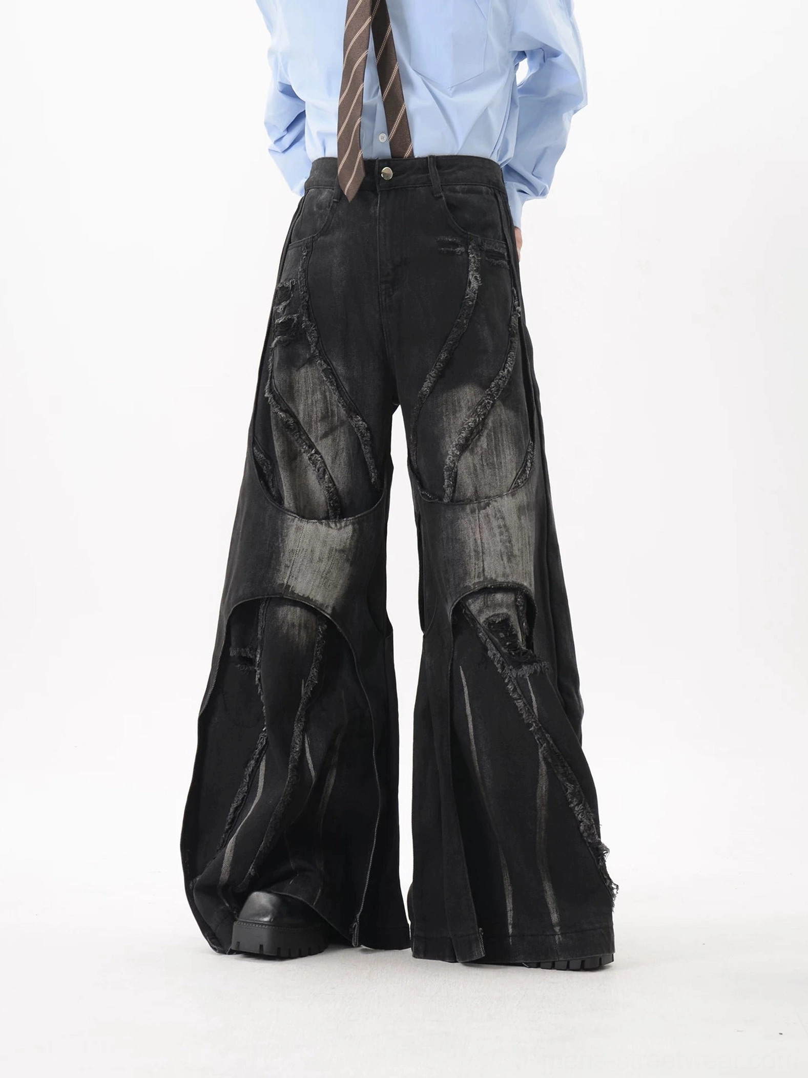 Right front three-quarter view of avant-garde wide-leg denim pants with asymmetrical panels, heavy faded black wash, and dramatic flared silhouette