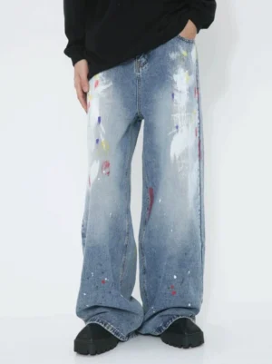 Front full-body view of avant-garde paint splatter wide-leg jeans in faded blue denim with white brush strokes and colorful details