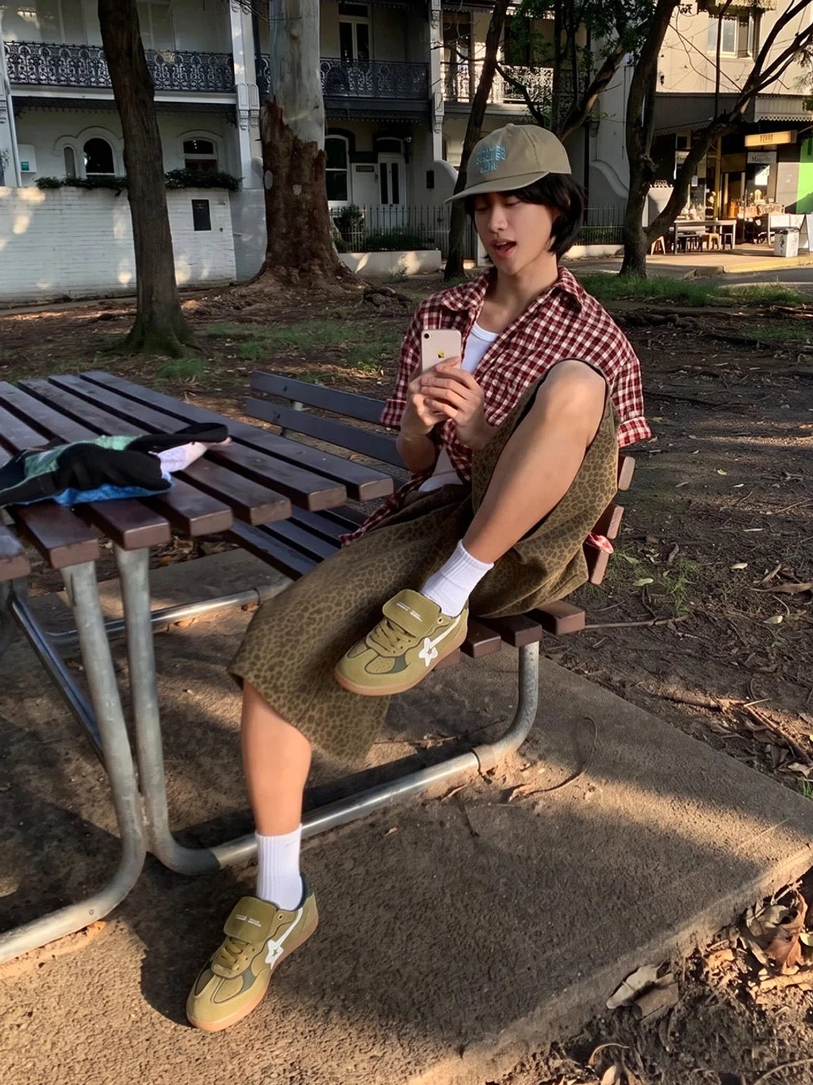 Male model styling avocado suede retro star sneakers with khaki trousers and a red checked shirt while seated outdoors