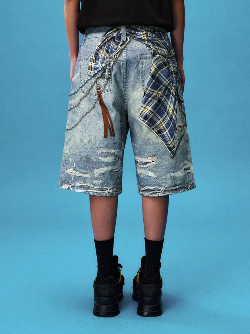Full back view of distressed plaid denim jorts featuring rear handkerchief detail, chain accents, leather-look tassel and loose fit