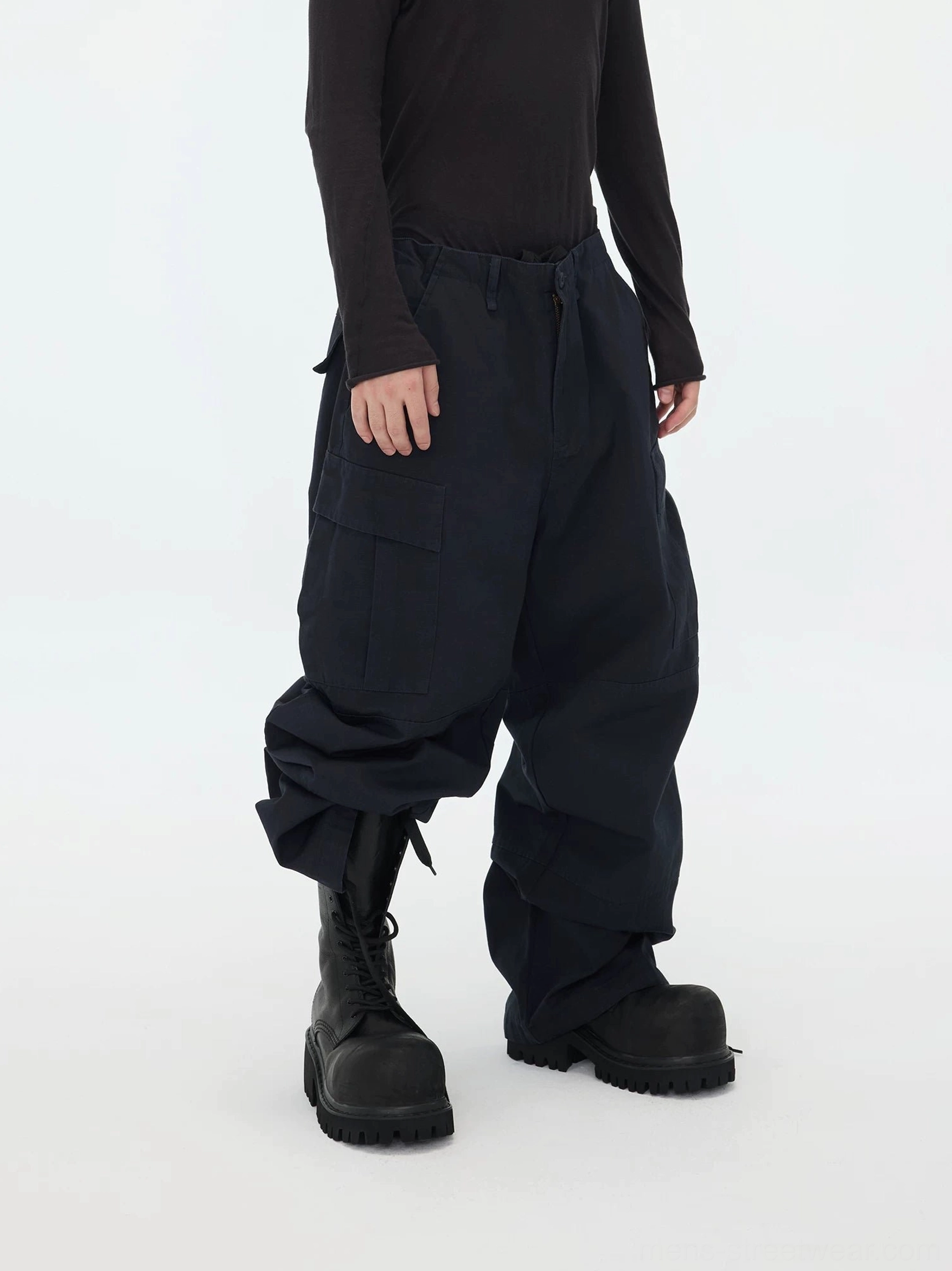 Left side view of baggy navy cargo pants featuring large flap cargo pockets, loose straight legs, mid-rise waistband, and adjustable drawcord cuffs