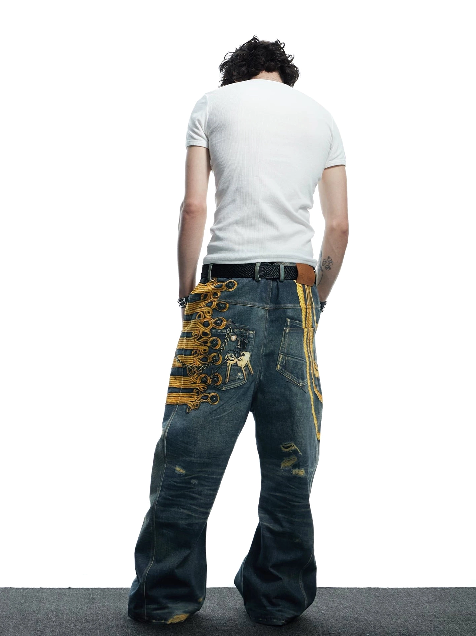 Full back view of embroidered distressed wide-leg jeans featuring vintage wash rear appliqué and decorative back pocket detail