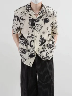 Centered front view of a model wearing a beige abstract print button-up short-sleeve shirt styled with striped trousers for modern Asian streetwear