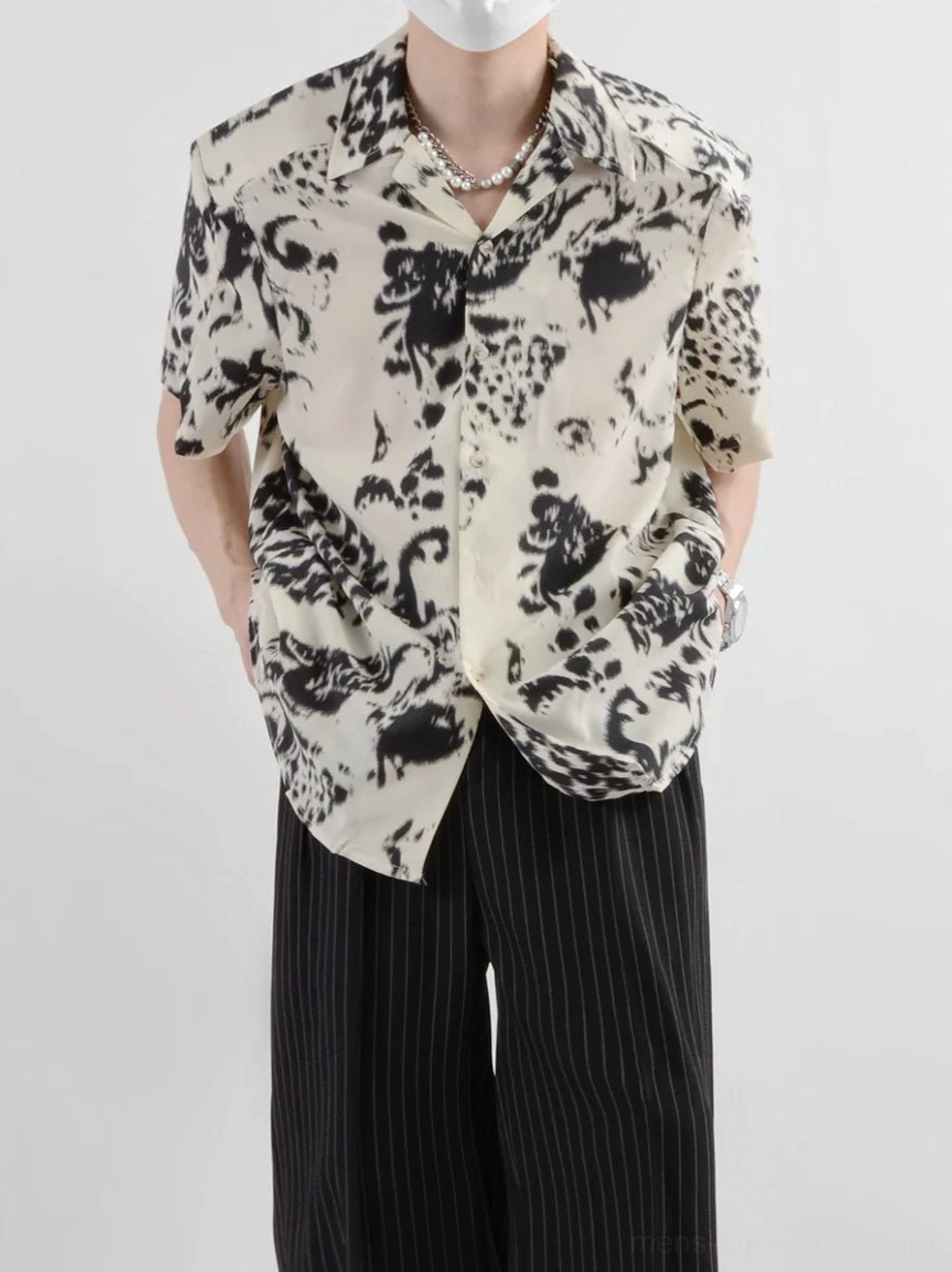 Centered front view of a model wearing a beige abstract print button-up short-sleeve shirt styled with striped trousers for modern Asian streetwear