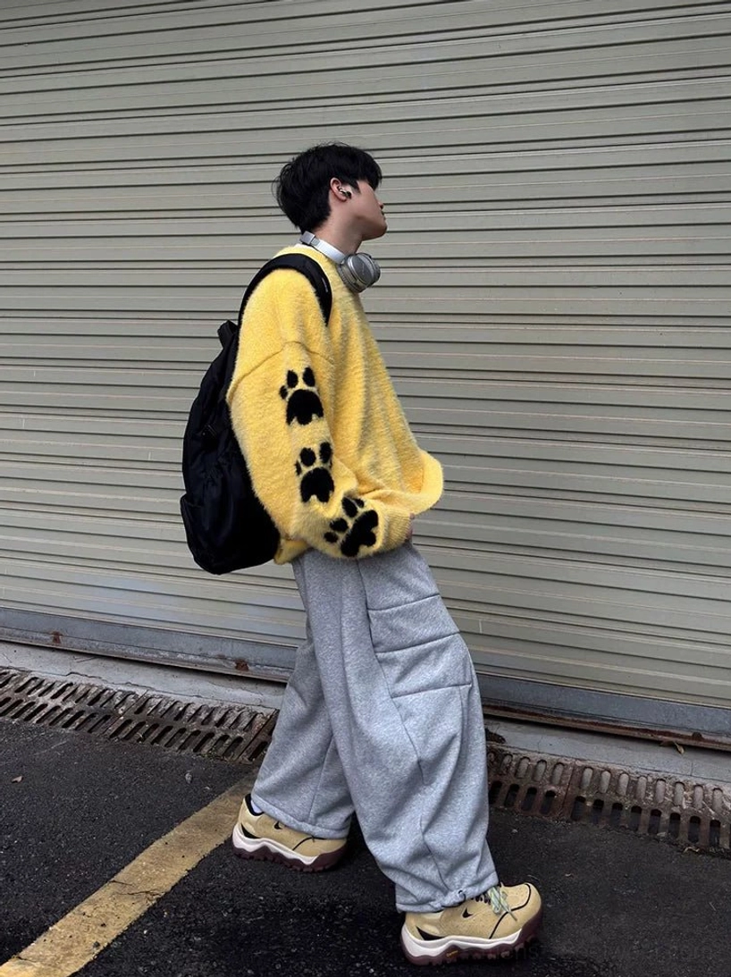 Beige chunky trail sneakers worn while walking with cargo pants and a backpack, showing the rugged outsole and urban gorpcore styling