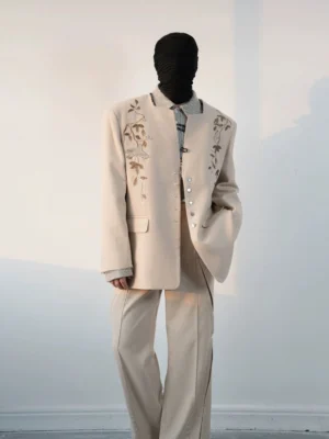 Three-quarter side view of a relaxed beige embroidered blazer suit with split hem flared trousers