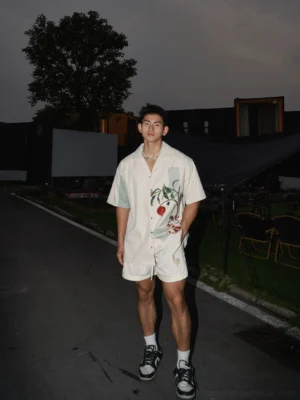 Front view of a beige botanical print summer shirt and matching shorts styled with sporty sneakers and crew socks for casual streetwear