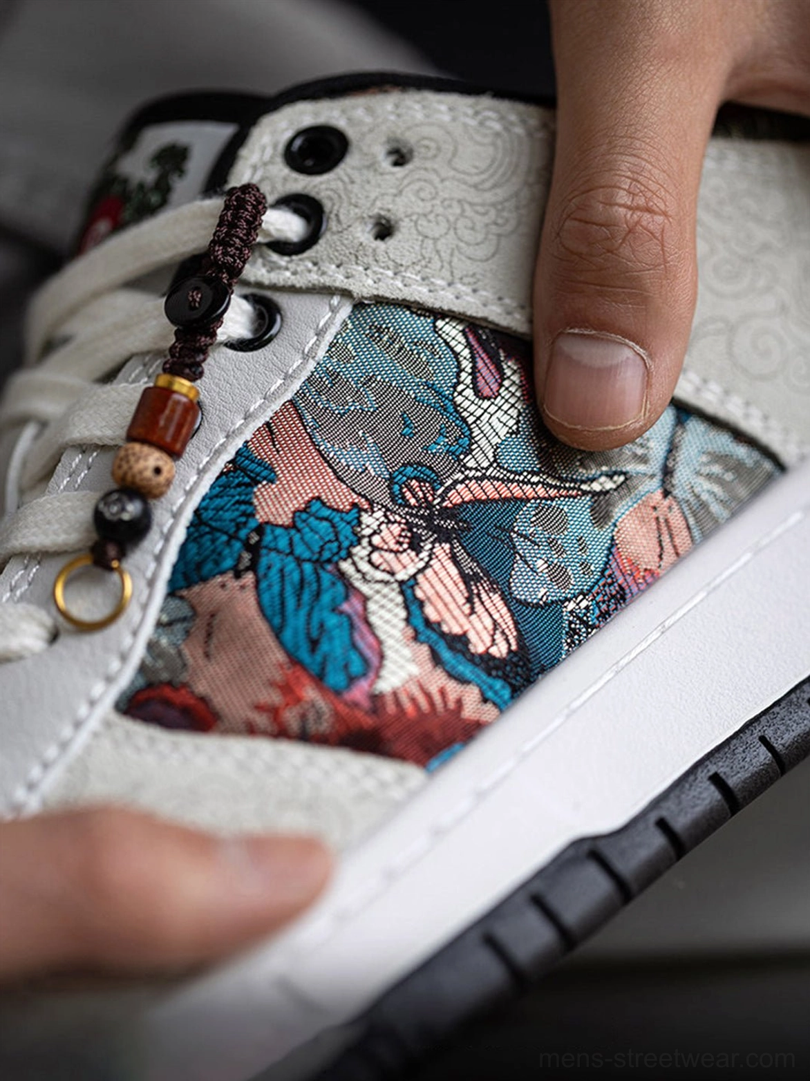 Extreme close-up of intricate bird embroidery, brocade side panel, textured upper, and decorative lace charm