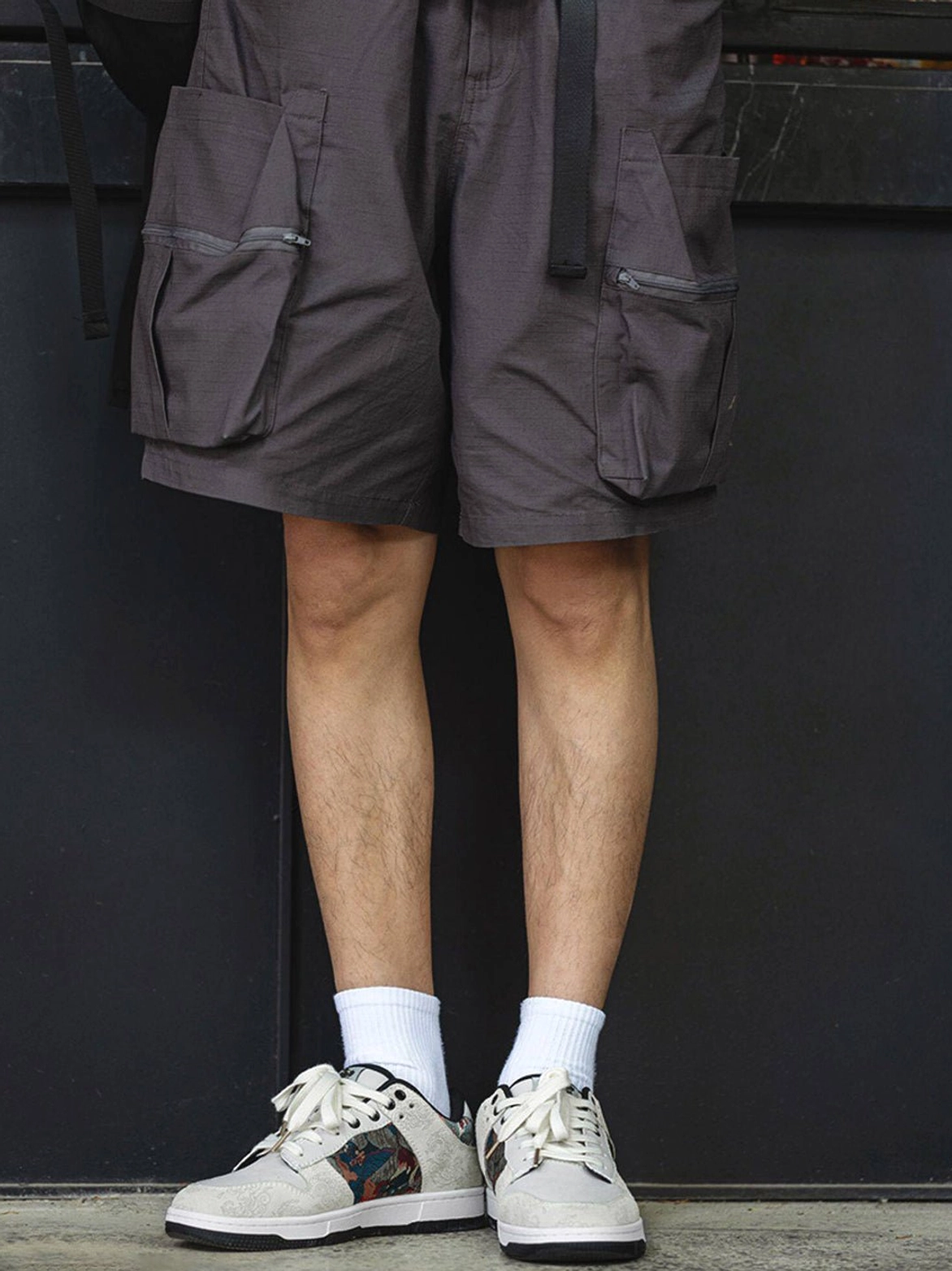 Full side view of embroidered white court sneakers worn with dark cargo shorts and white socks