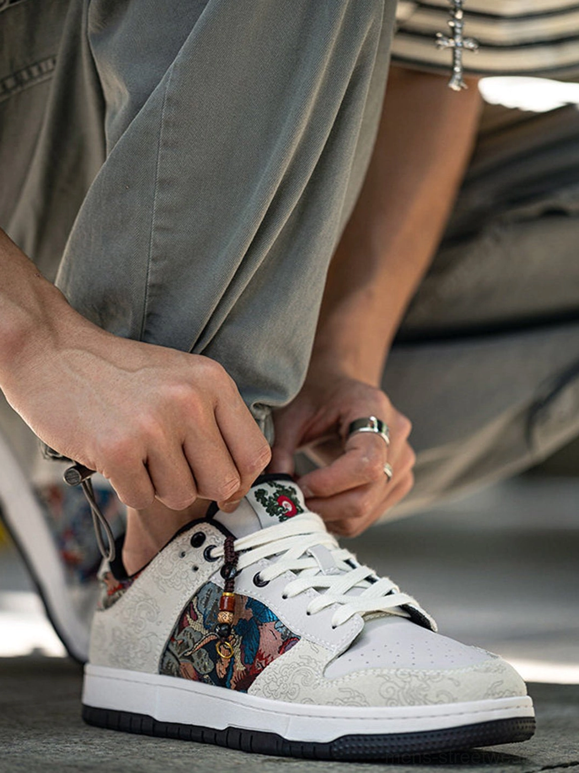 Close-up side view of white bird embroidered court sneakers showing brocade panel, lace-up design, and textured upper
