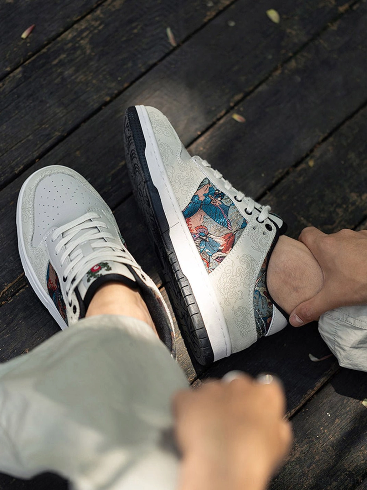Pair of white embroidered court sneakers viewed from above with visible brocade bird side panels and lace-up fronts