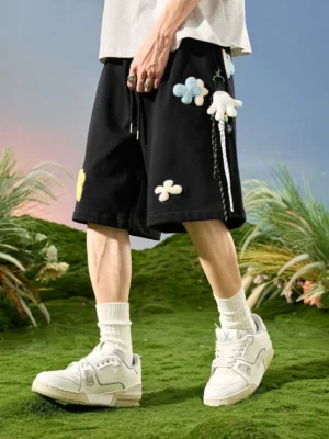 Black 3D floral appliqué drawstring sweat shorts front three-quarter view in outdoor streetwear setting