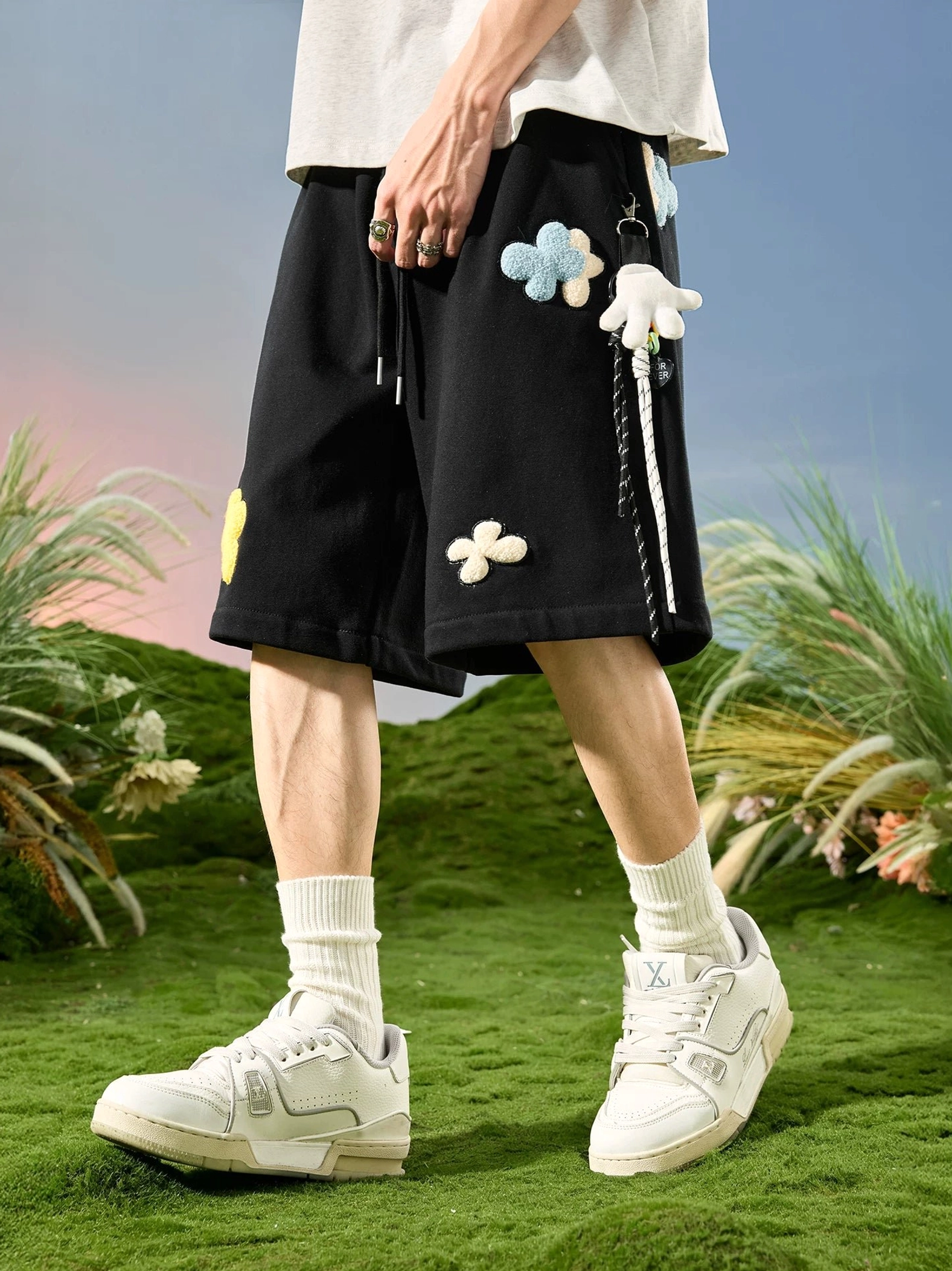 Black 3D floral appliqué drawstring sweat shorts front three-quarter view in outdoor streetwear setting