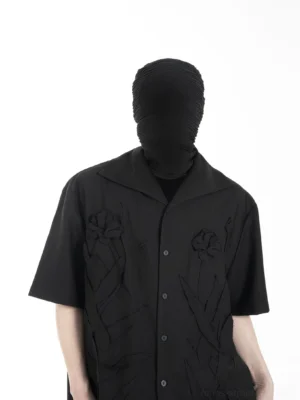 Front view of a black 3D floral embroidered camp collar shirt with short sleeves, button front, and relaxed streetwear fit on a male model