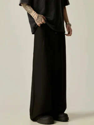 Black Acubi style high-waisted wide-leg trousers shown in a side-front view with concealed closure, fluid tailoring and thick-soled leather shoes