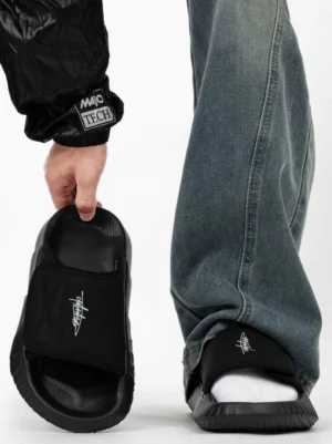 Black adjustable velcro platform slides with chunky EVA sole styled with baggy jeans in a minimalist streetwear studio look