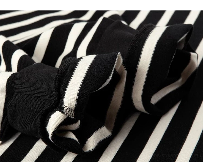 Close-up view of soft cotton knit fabric and folded sleeves from a black and apricot Breton stripe tee