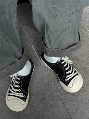 Black asymmetric toe platform canvas sneakers worn with grey cargo pants in an outdoor streetwear outfit top view