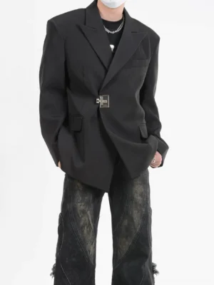 Three-quarter front view of a black men's asymmetric blazer showing the silver latch fastener, overlapping wrap front, relaxed tailored fit, and distressed wide-leg denim styling
