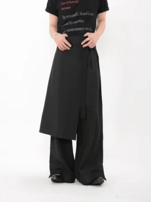 Front view of black asymmetric wrap layer wide leg trousers showing the clean high waist, wrap closure, and flowing streetwear silhouette