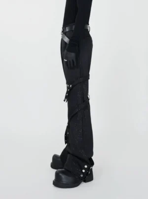 Side view of black avant-garde streetwear flare pants with spiral straps silver rivets glitter finish and industrial details