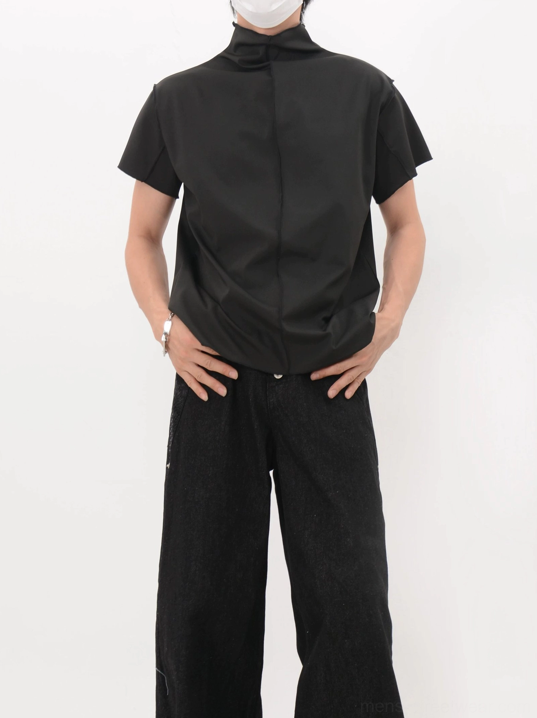 Side rear view of a black back seam mock neck shirt highlighting the relaxed shape and vertical center seam