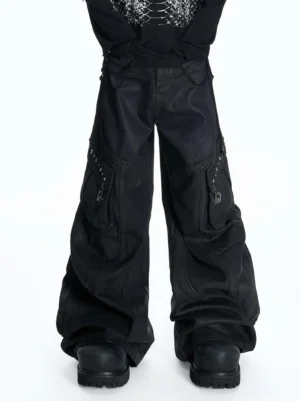 Low-angle front view of oversized washed black balloon cargo pants with ultra-wide legs, utility pockets, metal rivets, and black work boots