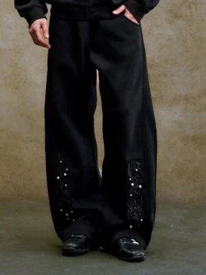 Black baroque pearl embroidered balloon wide-leg sweatpants shown from a low front angle with ornate floral embroidery at the hems