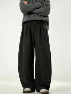 Male model wearing black belted wide-leg streetwear trousers with an oversized curved silhouette and mid-rise waist against a studio backdrop