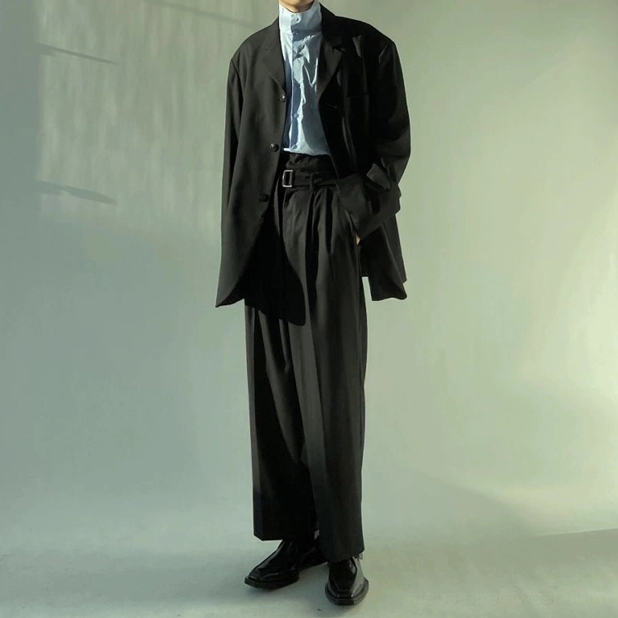 Black belted wide-leg suit trousers styled with an oversized black blazer, light blue dress shirt, and black leather shoes