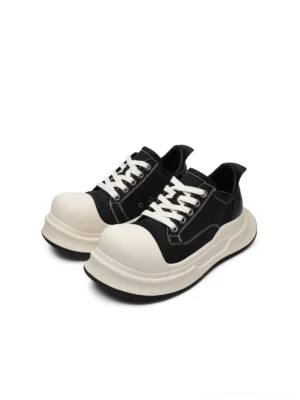 Front three-quarter view of black big-head round toe platform sneakers with off-white toe cap, contrast stitching, lace-up closure, and chunky 4 cm platform sole