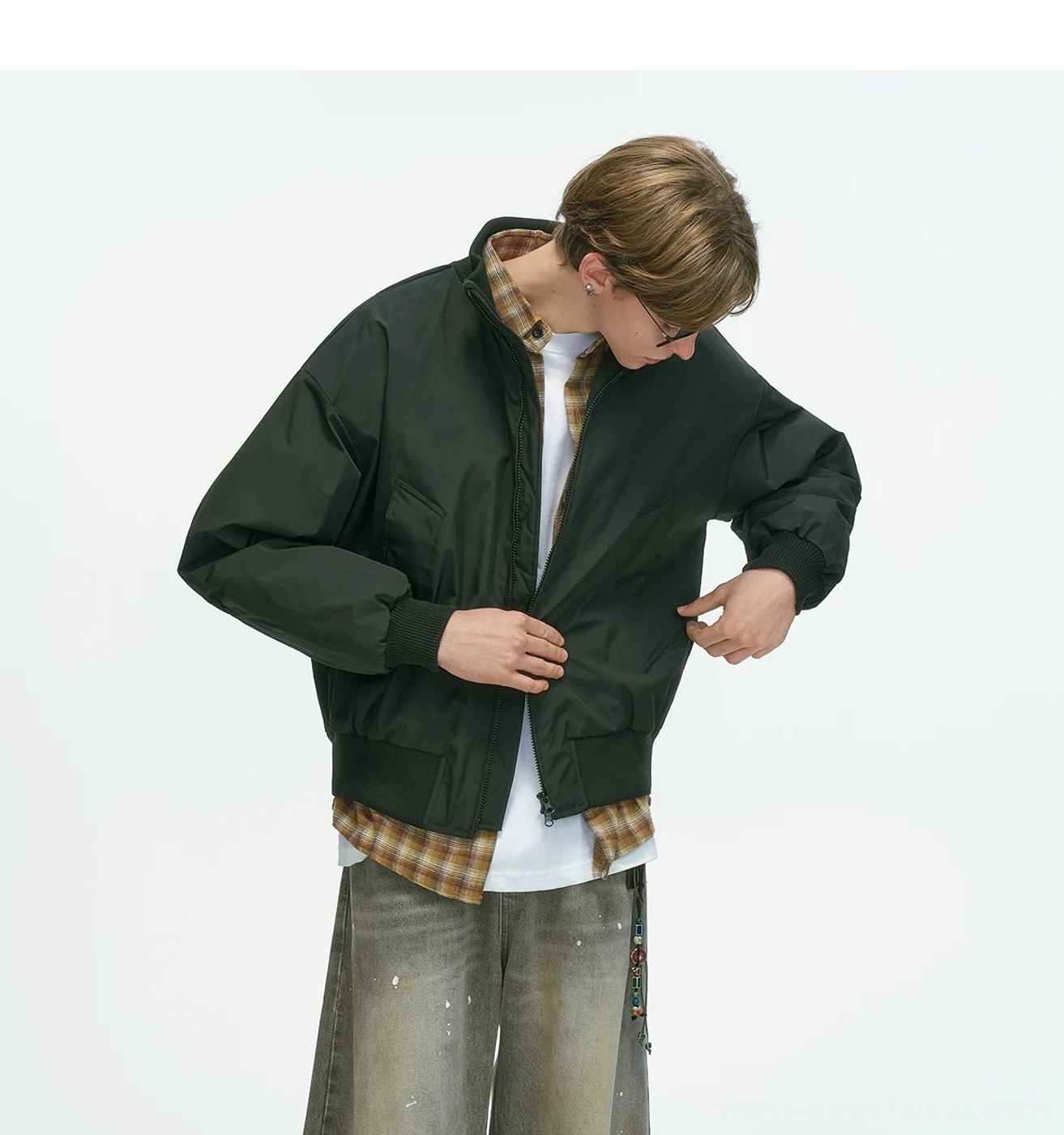Black bomber jacket slightly low three-quarter front shot with front zip closure and patch pockets, ribbed cuffs and hem, layered casual streetwear outfit