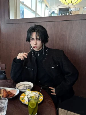 Black textured boucle jacket with pearl pocket details styled over a black turtleneck at a modern cafe