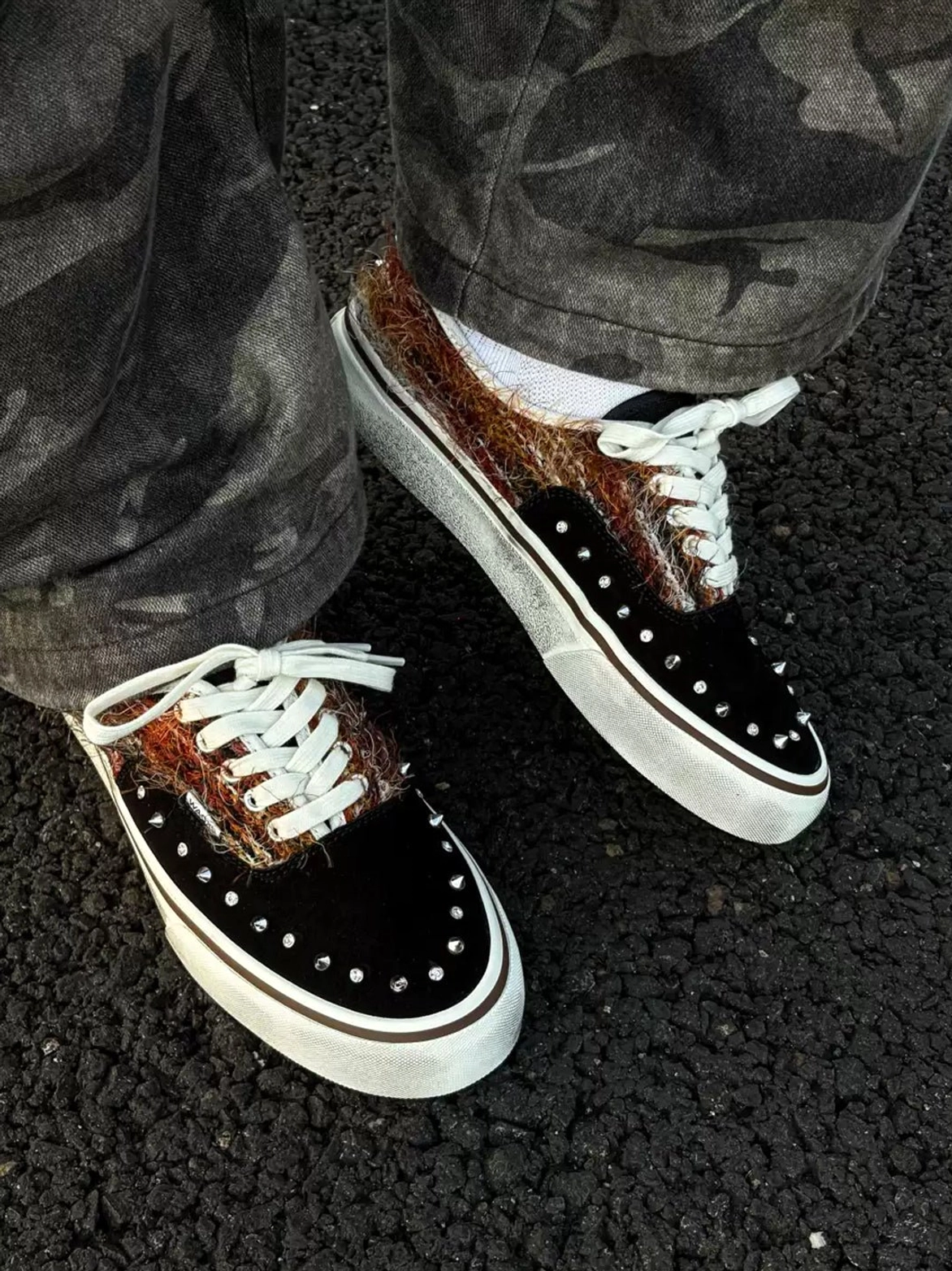 Pair of black and brown mohair-panel skate sneakers worn with camouflage cargo pants and white socks in a streetwear outfit