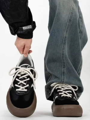 Two tone black and brown retro chunky sneakers with black suede toe cap white lace panels and thick gum rubber sole worn with baggy denim