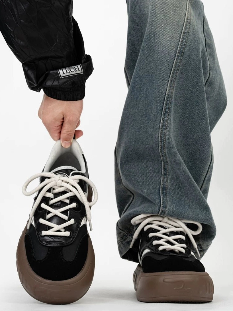 Two tone black and brown retro chunky sneakers with black suede toe cap white lace panels and thick gum rubber sole worn with baggy denim