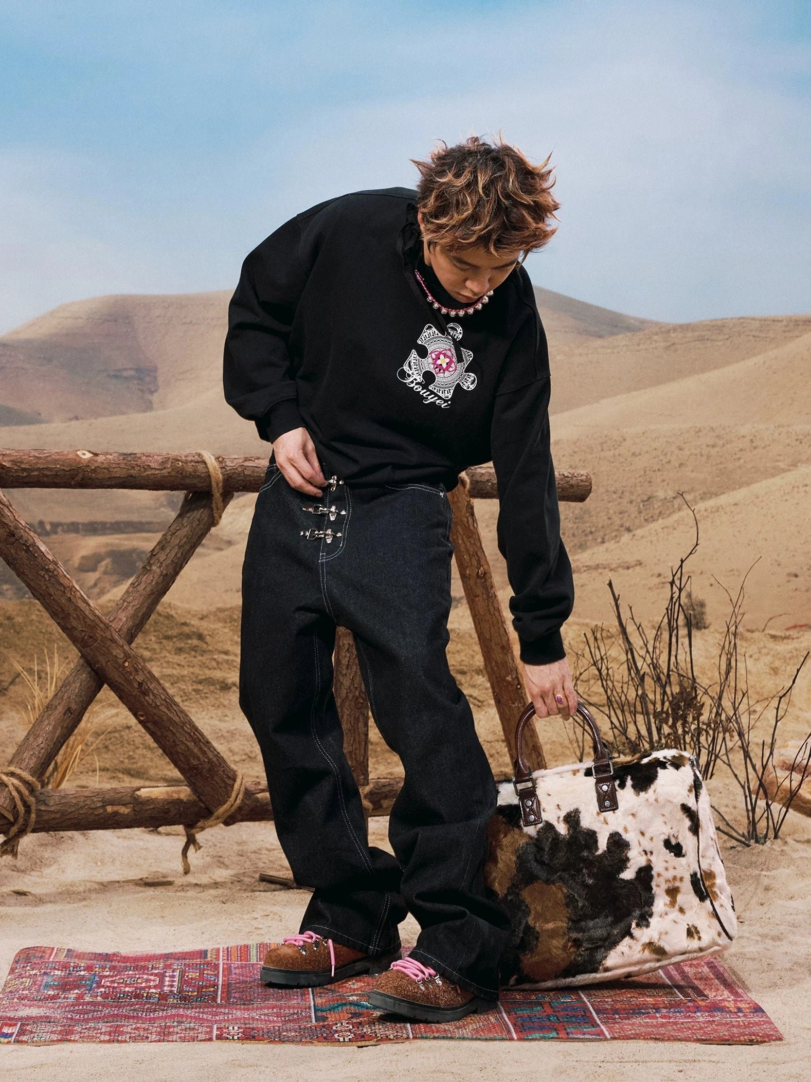 Side-front styling view of black buckle jeans with oversized graphic sweatshirt and red leather shoes
