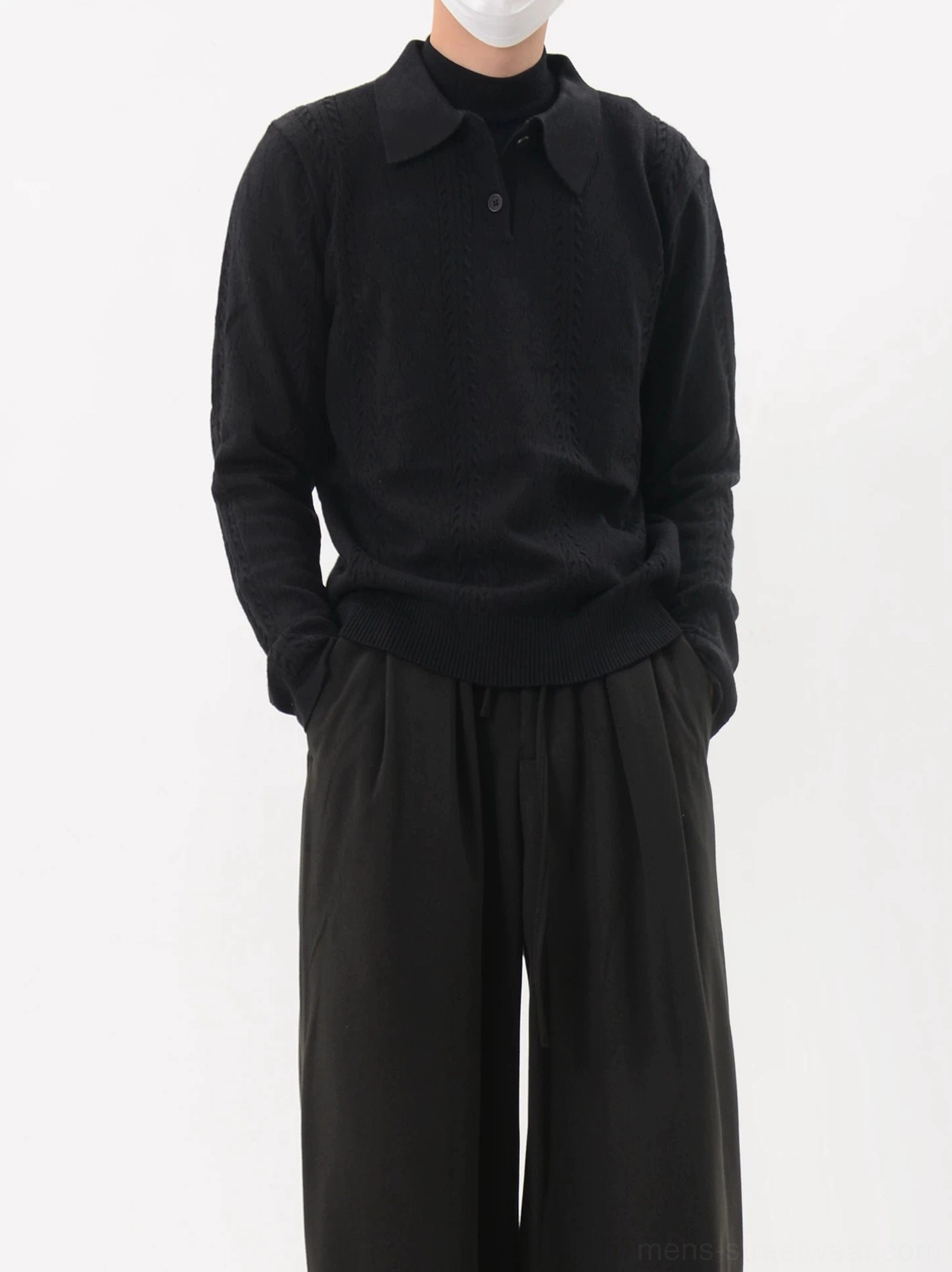 Pure black cable knit polo sweater shown in a front three-quarter view with twisted knit texture and modern slim streetwear silhouette