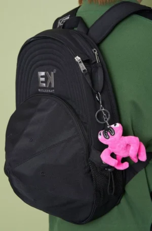Black canvas baseball cap backpack worn from a back three-quarter view with mesh side pocket and adjustable shoulder straps
