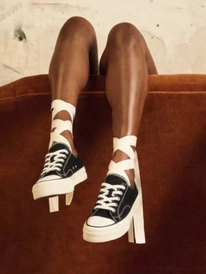 Black canvas platform sneakers worn with crisscross ribbon socks in a vintage streetwear lifestyle setting